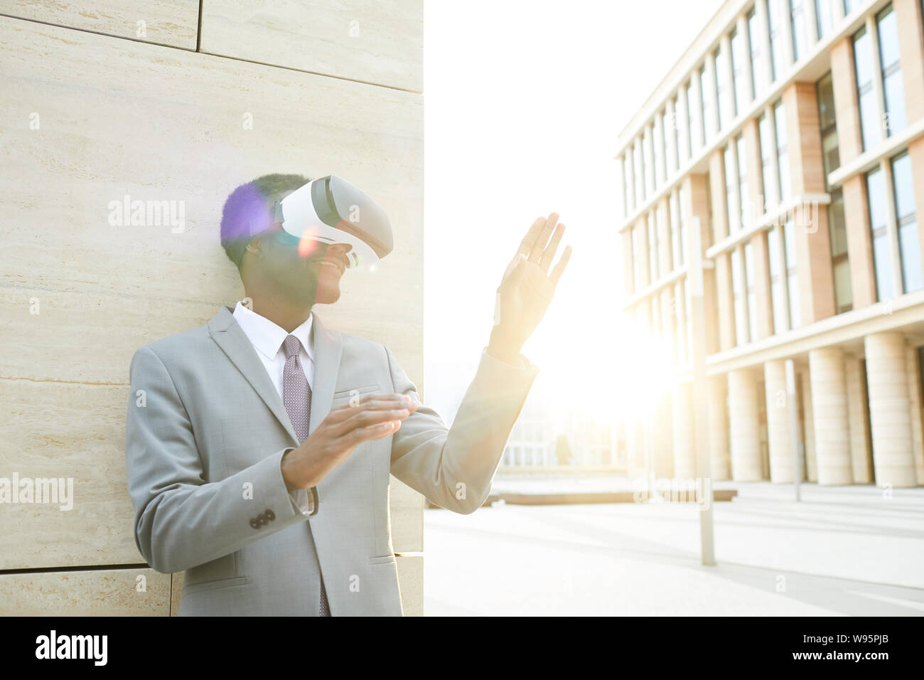 African young businessman wearing goggles and playing in virtual game ...