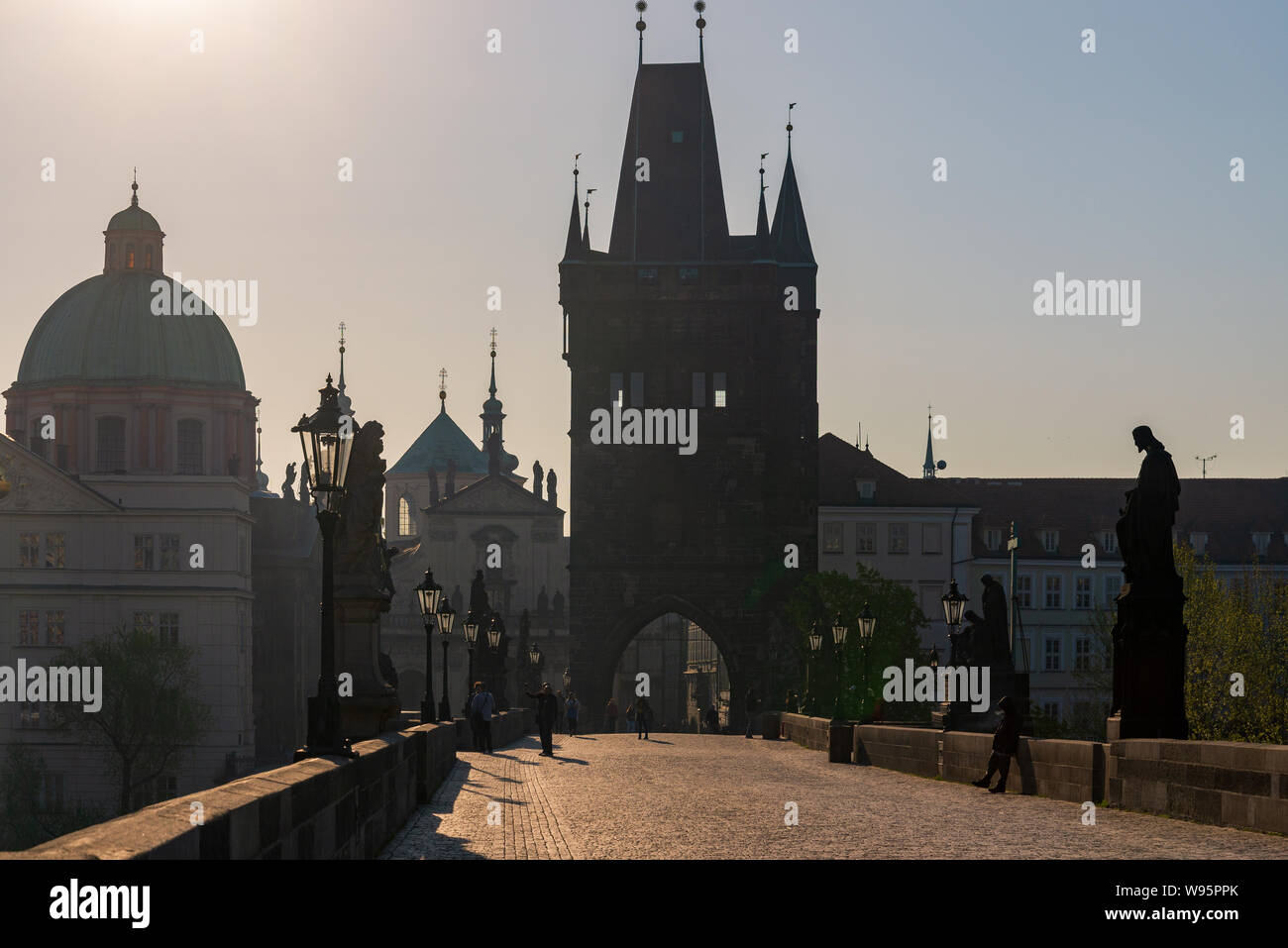 Silhouette view of people enjoy beautiful sunny day on Charles Bridge, and background of Old Town Bridge Tower and Church of St. Salvator in morning. Stock Photo