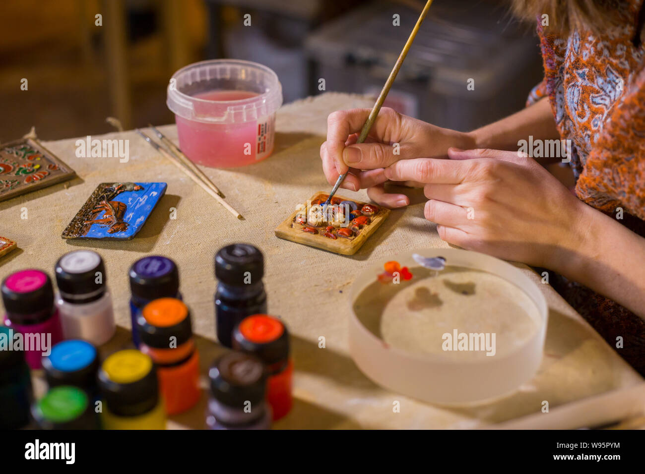 Professional woman potter painting ceramic souvenir magnet in potter Stock Photo