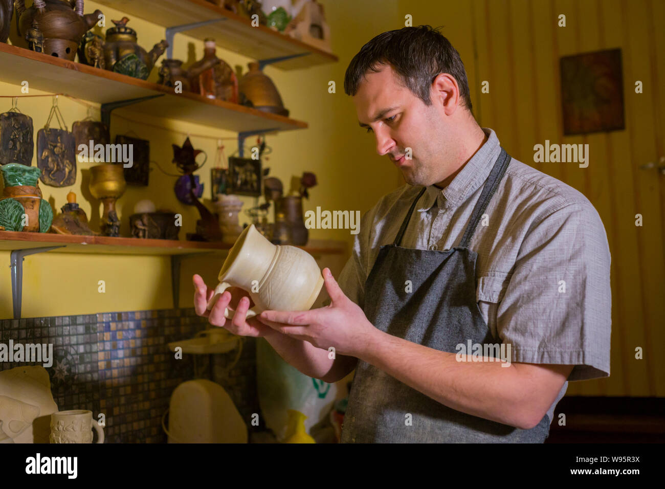 Professional male potter examining jug in pottery workshop Stock Photo ...