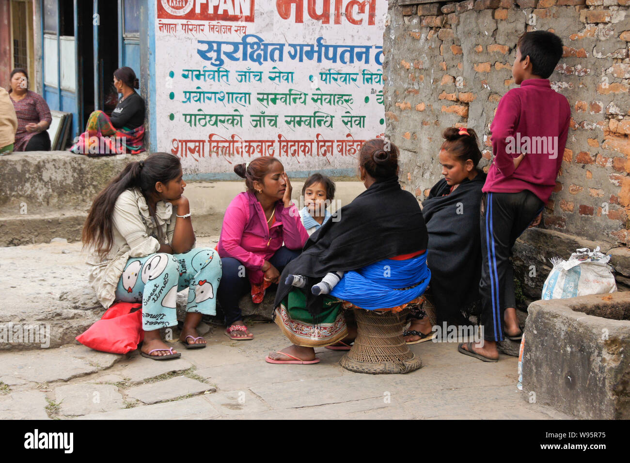 People socialize outside a shop in the Old Bazaar area of Pokhara, Nepal Stock Photo