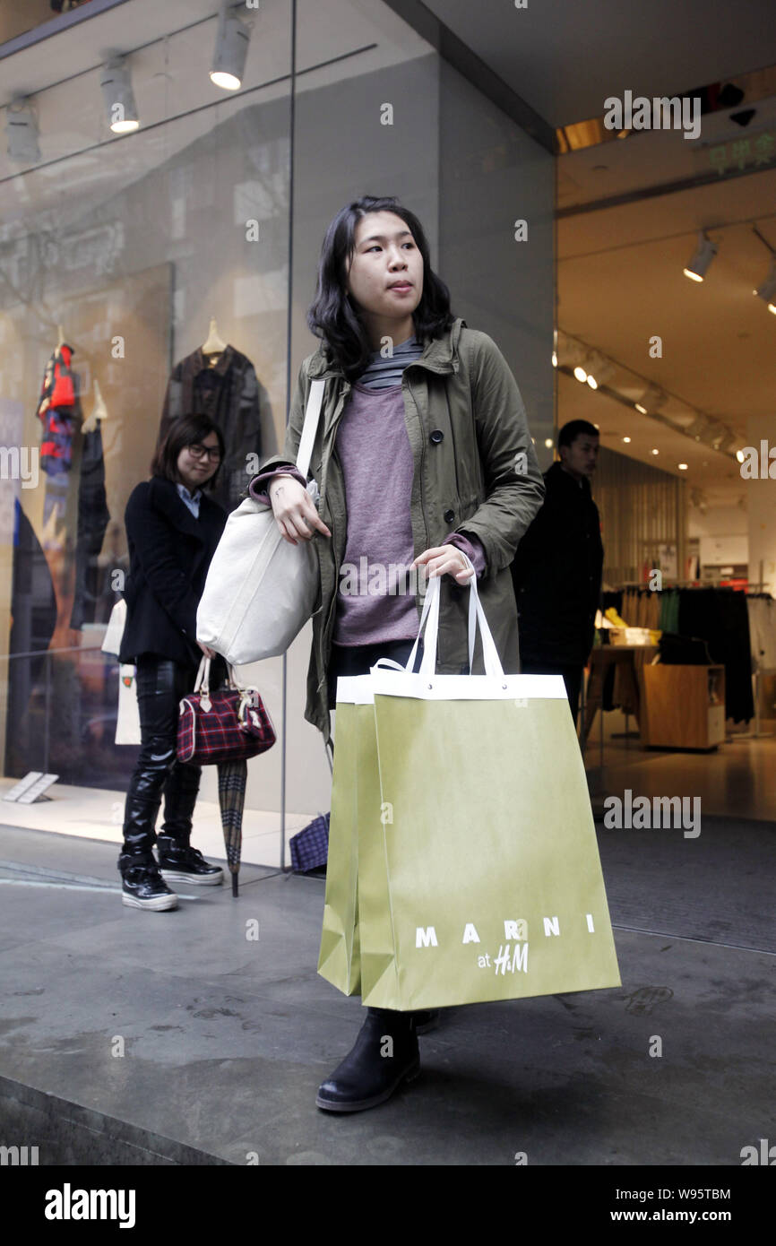A shopper who bought the new collections by Marni and H&M walks out from an  H&M store in Shanghai, China, 8 March 2012. Shoppers queued from before  Stock Photo - Alamy