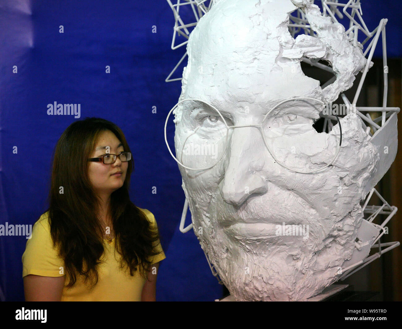 A visitor looks at an artwork in the shape of the face of deseased