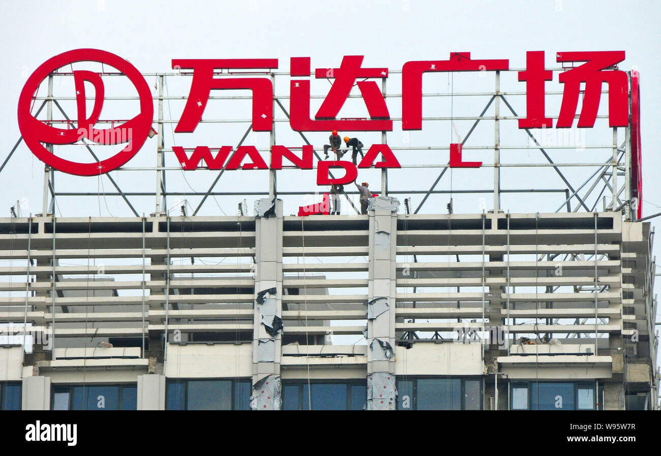 --FILE--Chinese workers install the signage of Wanda Plaza on the top of a building in Fuzhou city, southeast Chinas Fujian province, 21 October 2011. Stock Photo