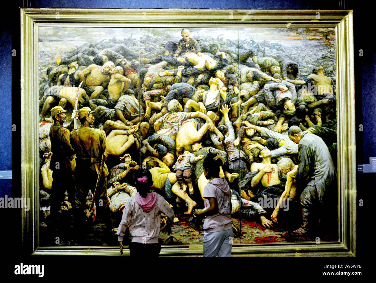 Visitors look at the oil painting, Nanking Massacre, by artist Li Zijian during an exhibition in Shenyang city, northeast Chinas Liaoning province, 10 Stock Photo