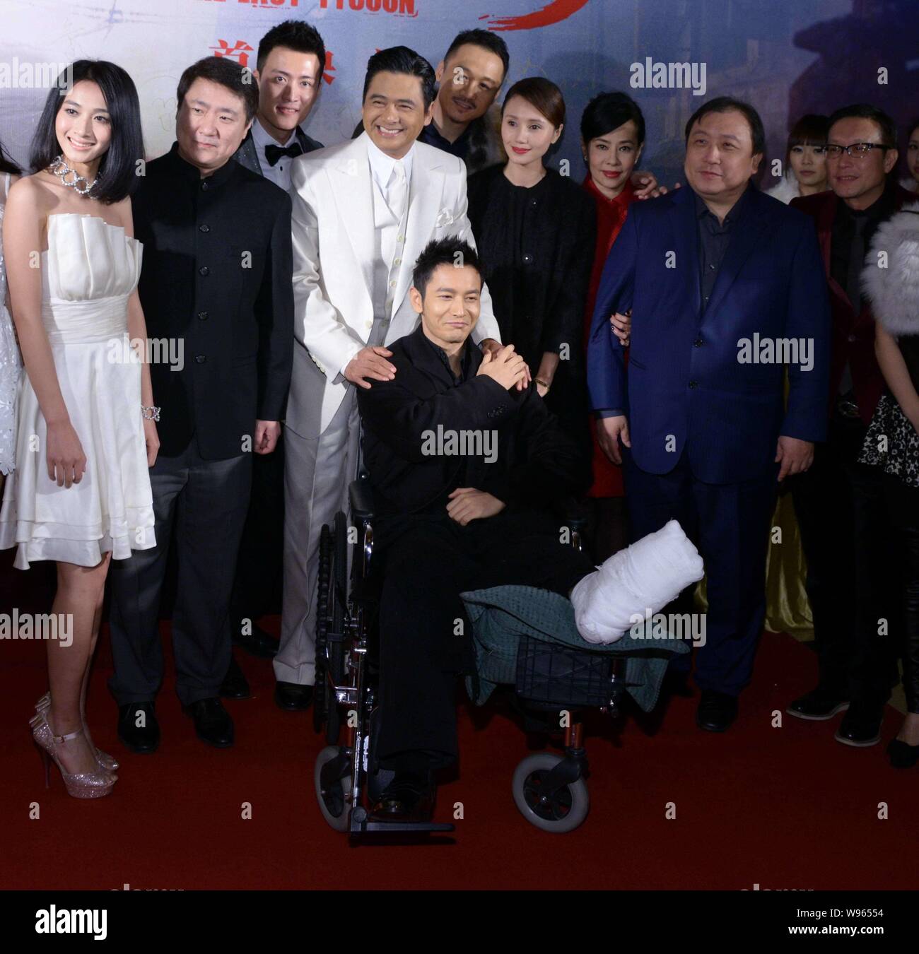 Hong Kong actor Chow Yun-fat, fourth left, poses with Chinese actor Huang Xiaoming, front, whose right leg and foot were injured and other cast member Stock Photo