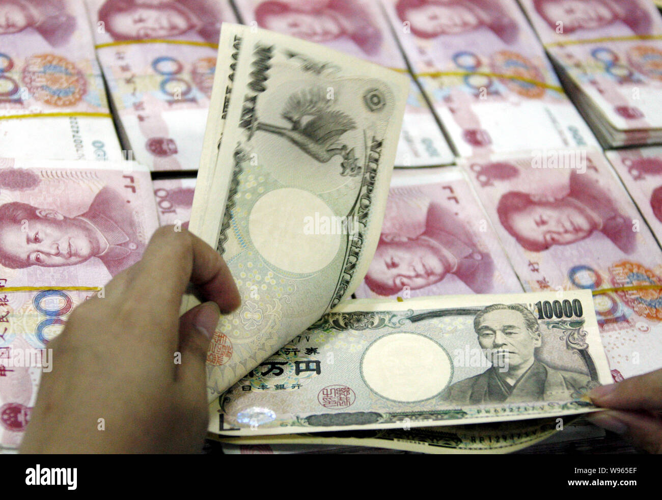 A Chinese bank clerk counts Japanese Yan banknotes over RMB (renminbi) yuan  banknotes at a bank in Huaibei city, east Chinas Anhui province, August 17  Stock Photo - Alamy