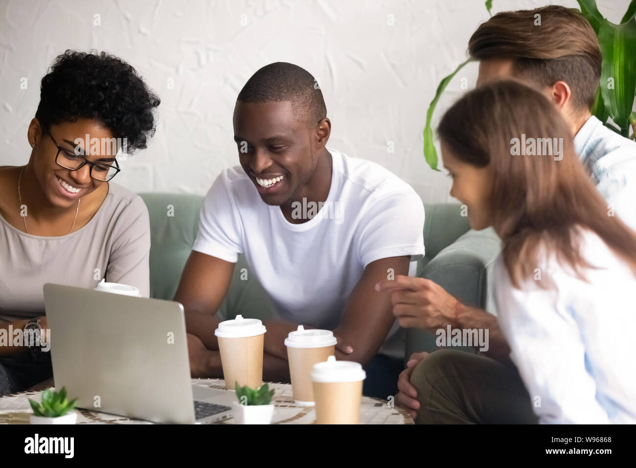 Happy diverse friends laugh hanging out in cafe Stock Photo