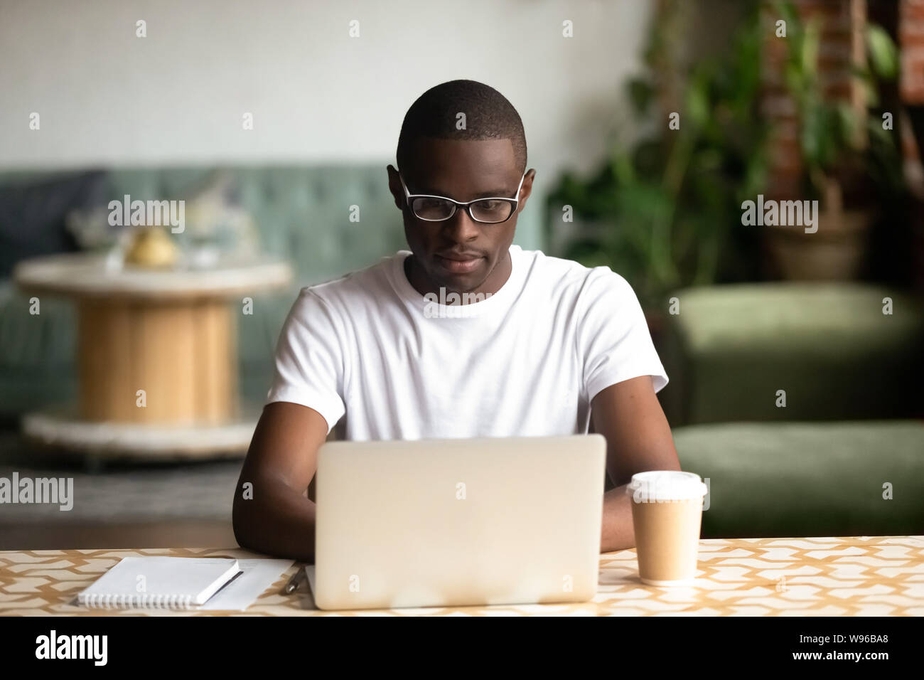 Focused black man studying on laptop drinking coffee Stock Photo