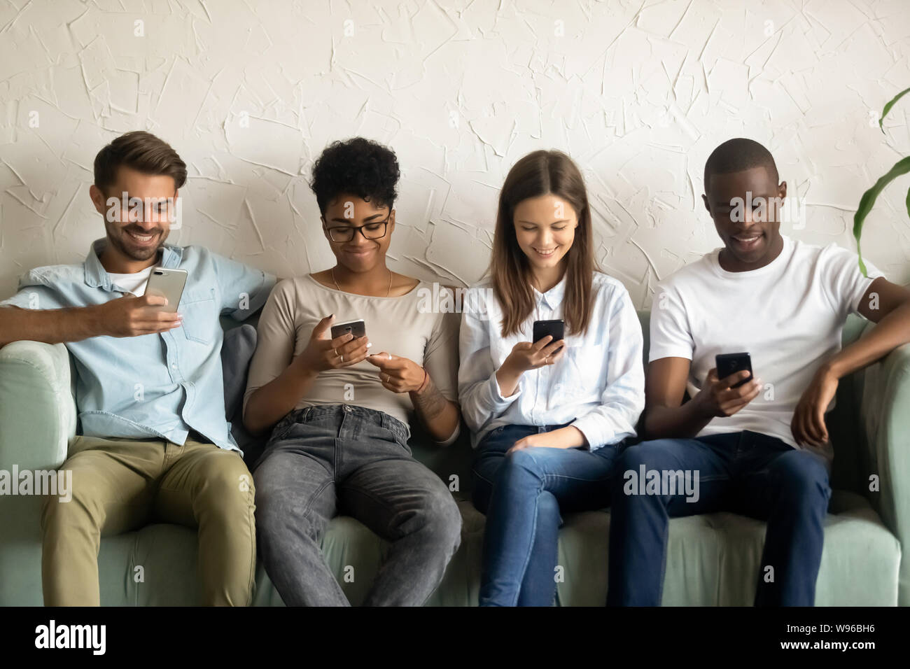 Multiracial young people using smartphones waiting in queue Stock Photo