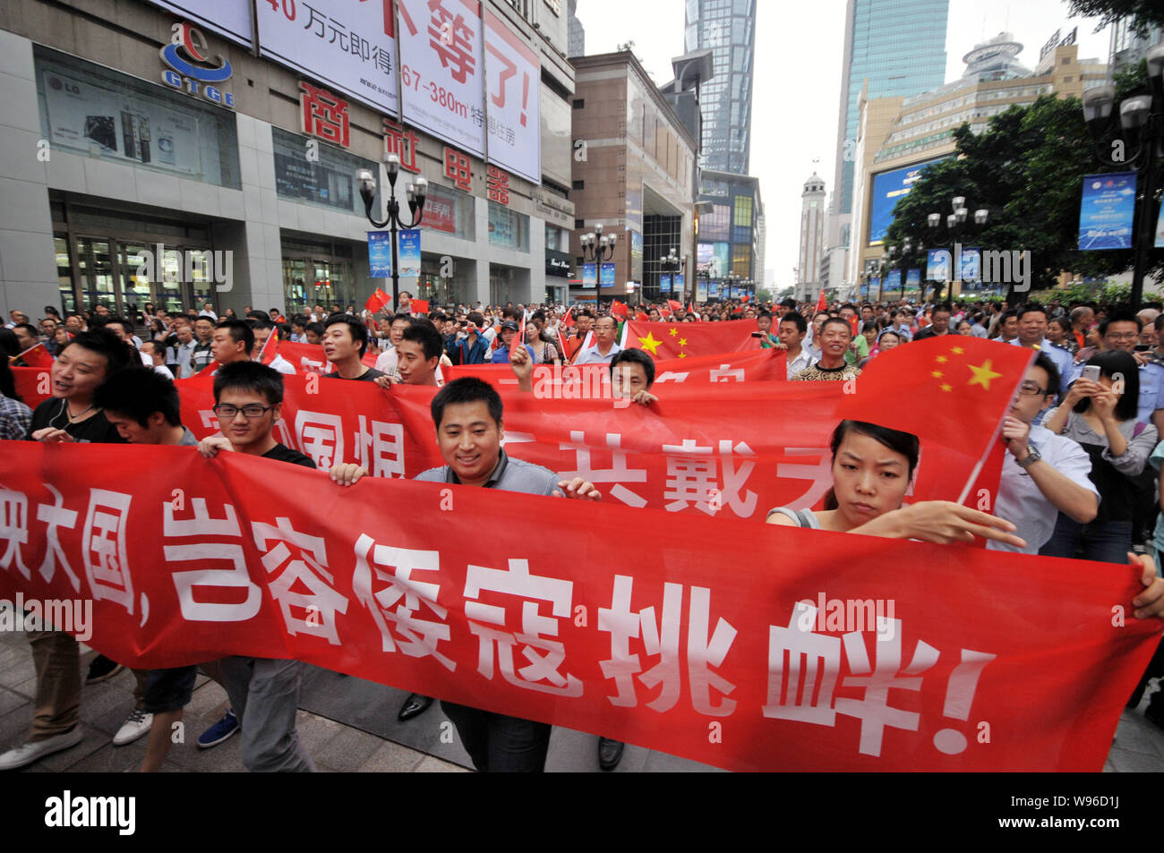 Chinese protestors wave Chinese national flags, hold up banners and shout slogans during an anti-Japan protest parade in Chongqing, China, 16 Septembe Stock Photo