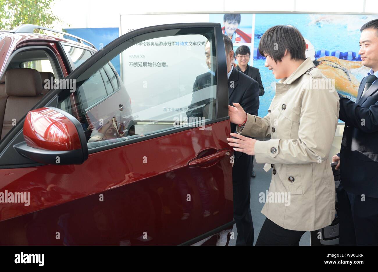 Chinese Olympic swimming champion Ye Shiwen, center, opens the door of her BMW X5 during a delivery ceremony at a BMW dealership in Hangzhou city, eas Stock Photo