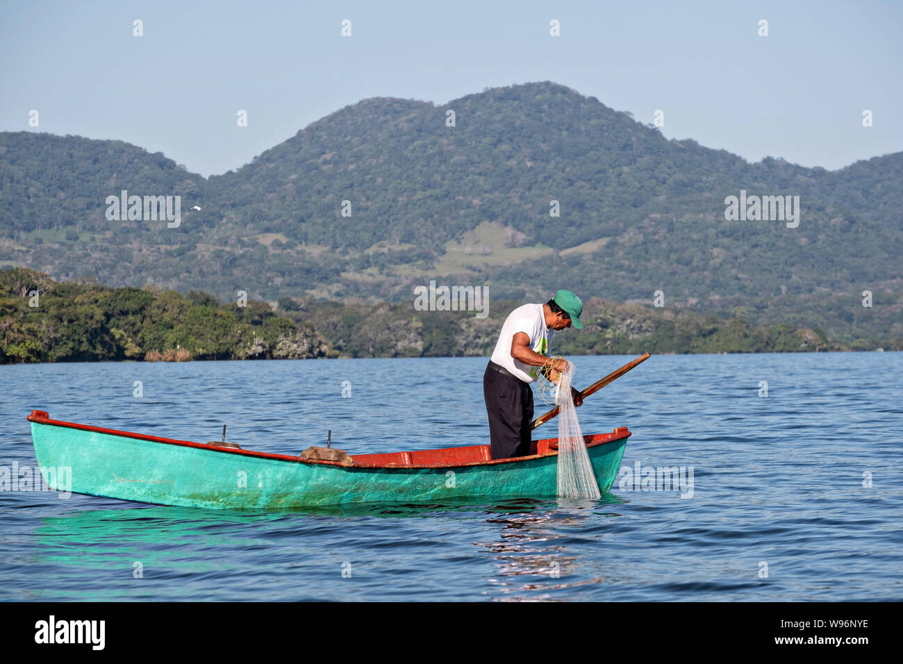 A fisherman prepares to cast a net into Lake Catemaco in Catemaco, Veracruz, Mexico. The tropical freshwater lake at the center of the Sierra de Los Tuxtlas, is a popular tourist destination and known for free ranging monkeys, the rainforest backdrop and Mexican witches known as Brujos. Stock Photo