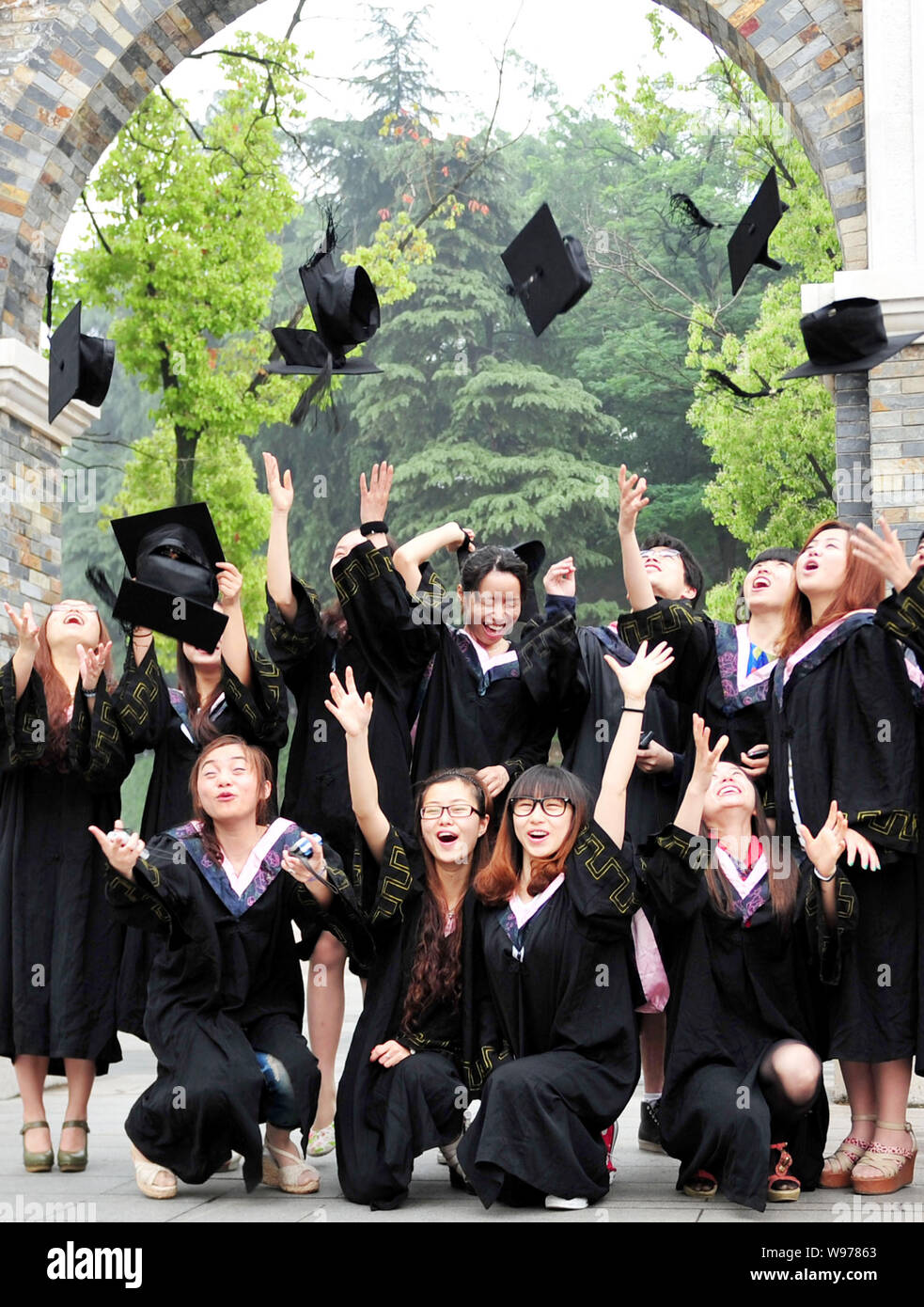 Chinese students dressed in graduation uniforms throw academic hats
