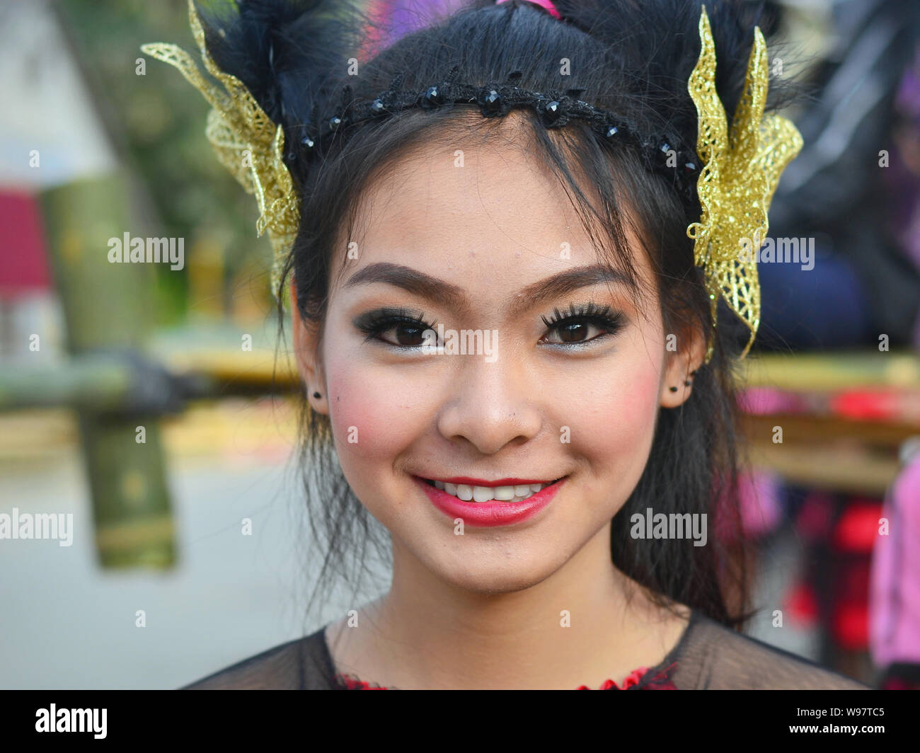 Costumed pretty Thai girl takes part in the village's historical Lanna street parade and smiles for the camera. Stock Photo