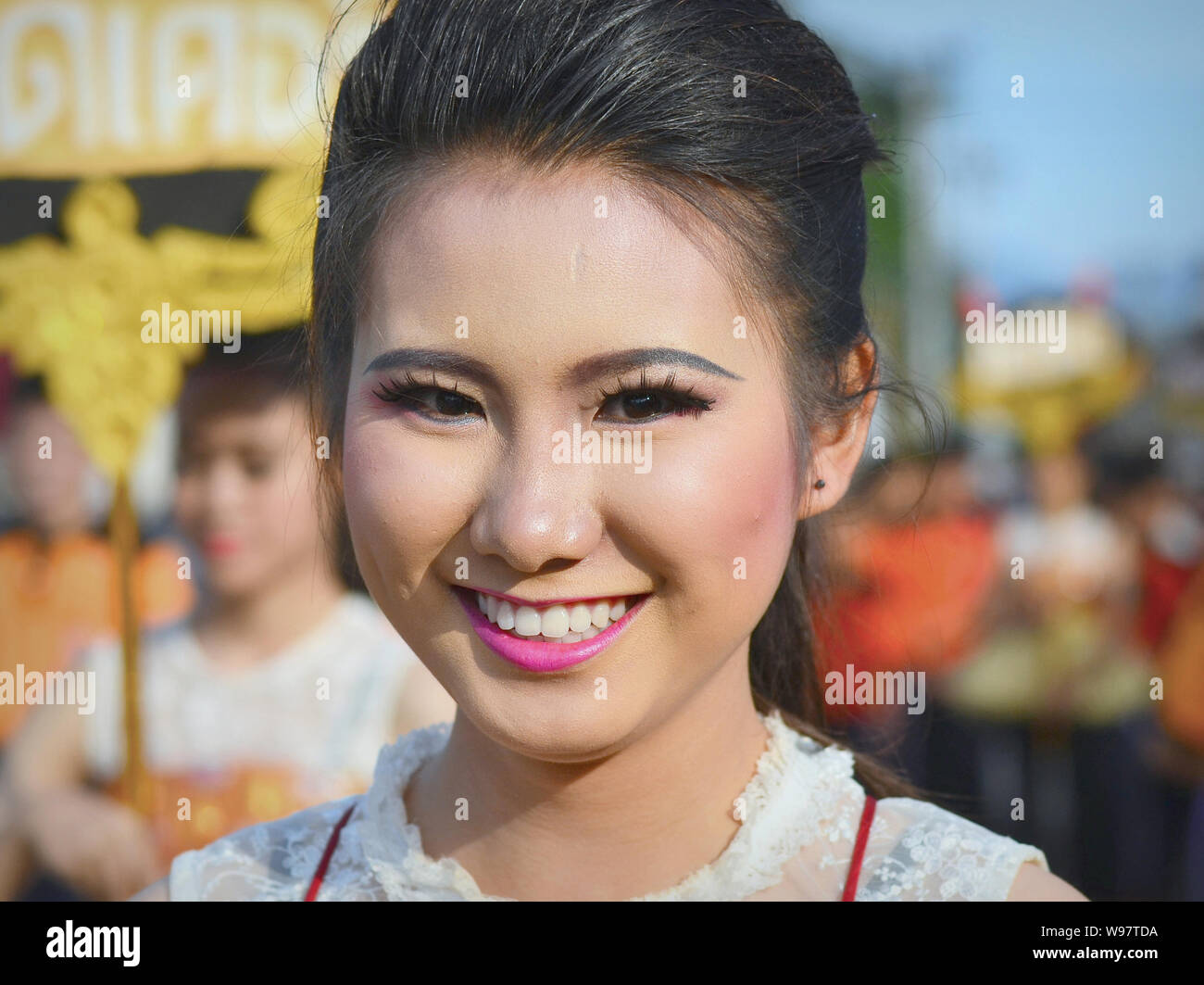Dressed-up pretty Thai girl takes part in the village's historical Lanna street parade and smiles for the camera. Stock Photo