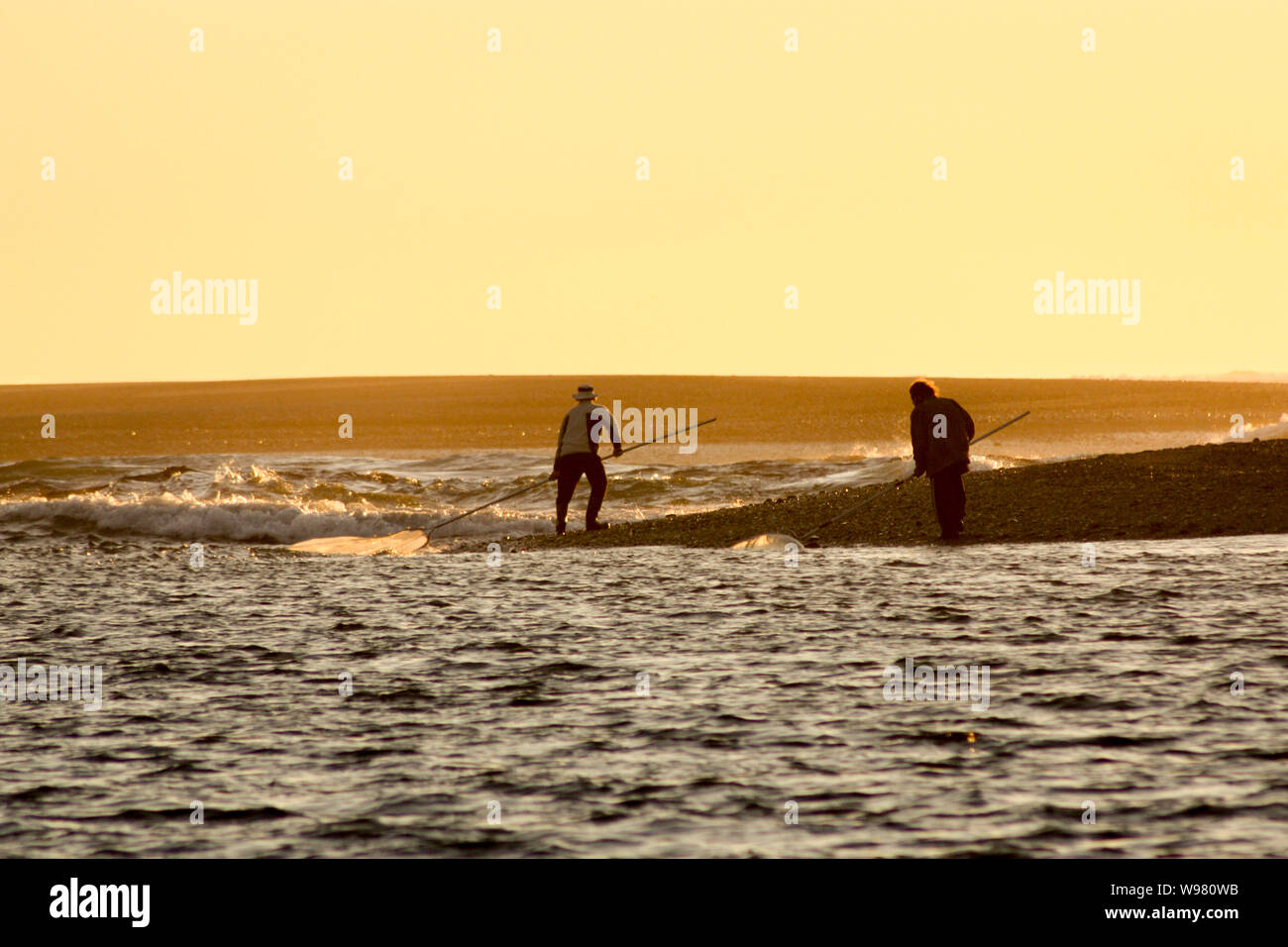 Whitebaiters fish on the rising tide at the Hokitika River mouth at sunset in New Zealand Stock Photo