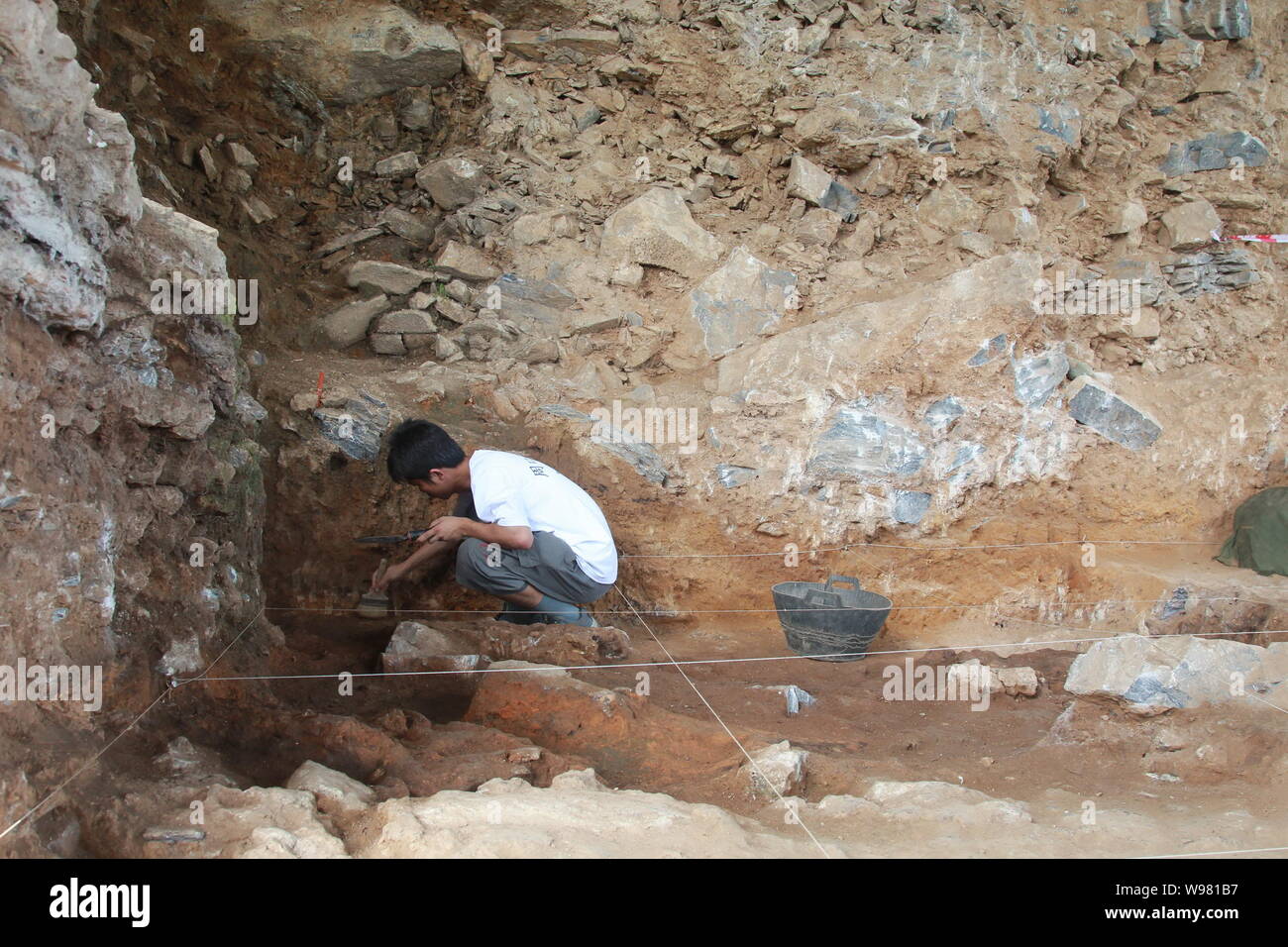 An archeologist checks for relics at Zhoukoudian in a suburb of Beijing, capital of China, 8 August 2011.    A further excavation was launched in May Stock Photo