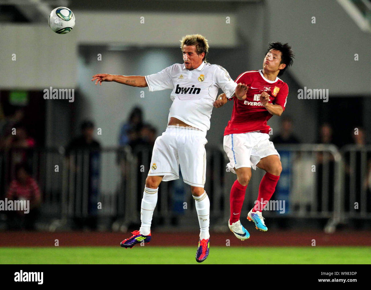Fabio Coentrao of Real Madrid, left, challenges Feng Junyan of Guangzhou Evergrande in a friendly soccer match in Guangzhou city, south Chinas Guangdo Stock Photo
