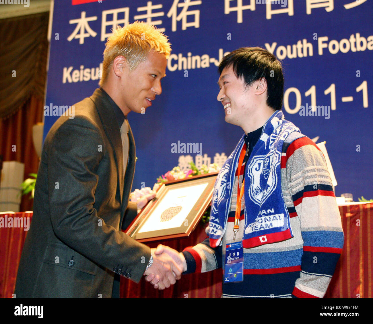Japanese football player Keisuke Honda, left, shakes hands with a soccer fan at a press conference for the China-Japan Youth Football Exchange Program Stock Photo