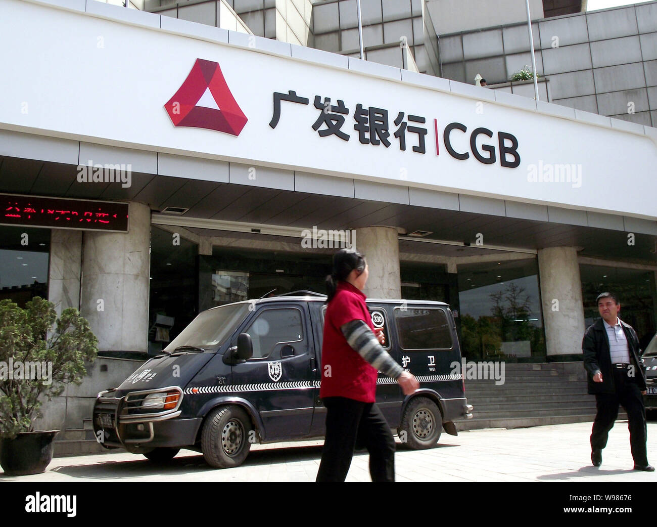 --FILE--Local Chinese residents walk past a branch of Guangdong Development Bank (CGB) with the new logo in Nanjing city, east Chinas Jiangsu province Stock Photo