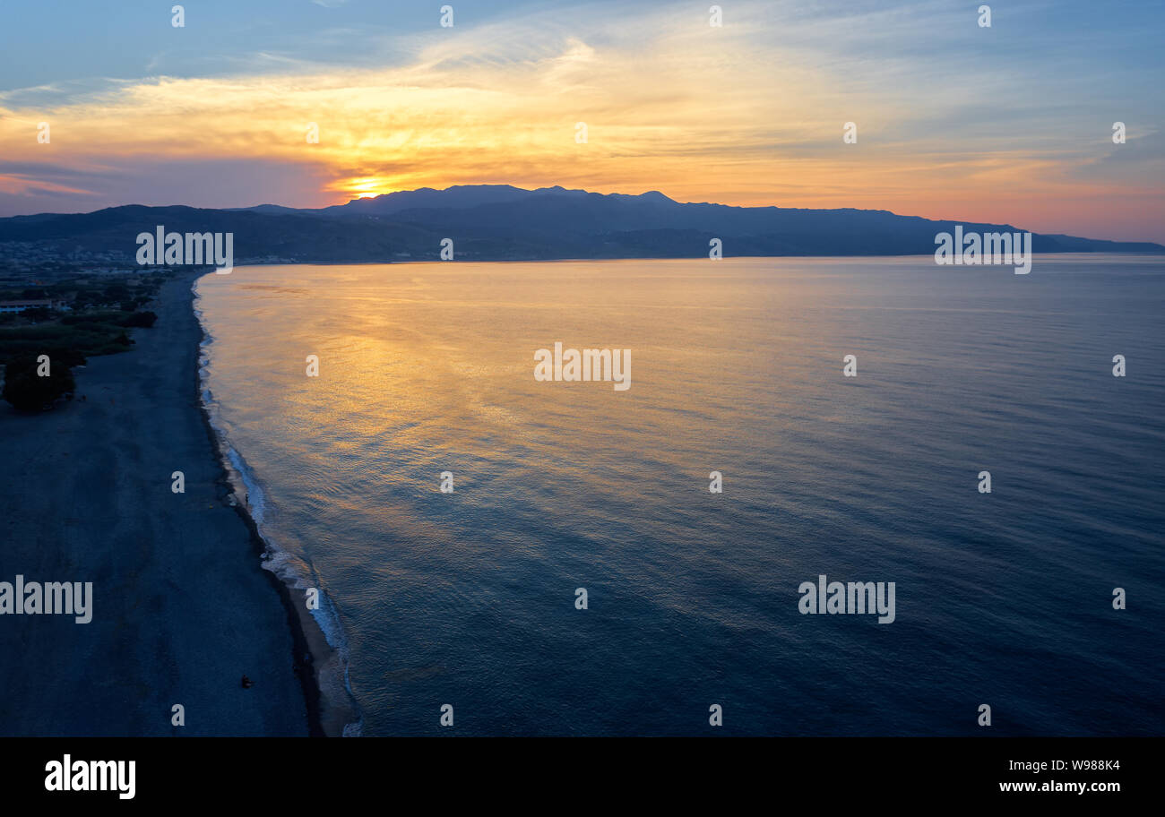 Aerial view from drone on Platanias beachfront area, beach and sea at sunset time. Rodopos peninsula is on background. Chania prefecture, Crete, Greec Stock Photo