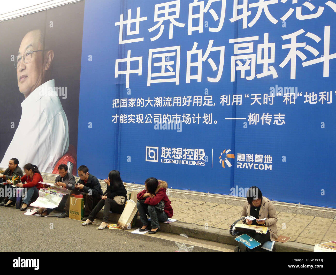 File--Local residents sit in front of an advertisement of Legend Holdings  with a picture of Liu Chuanzhi, Chairman of Legend Holdings Ltd, during a  Stock Photo - Alamy