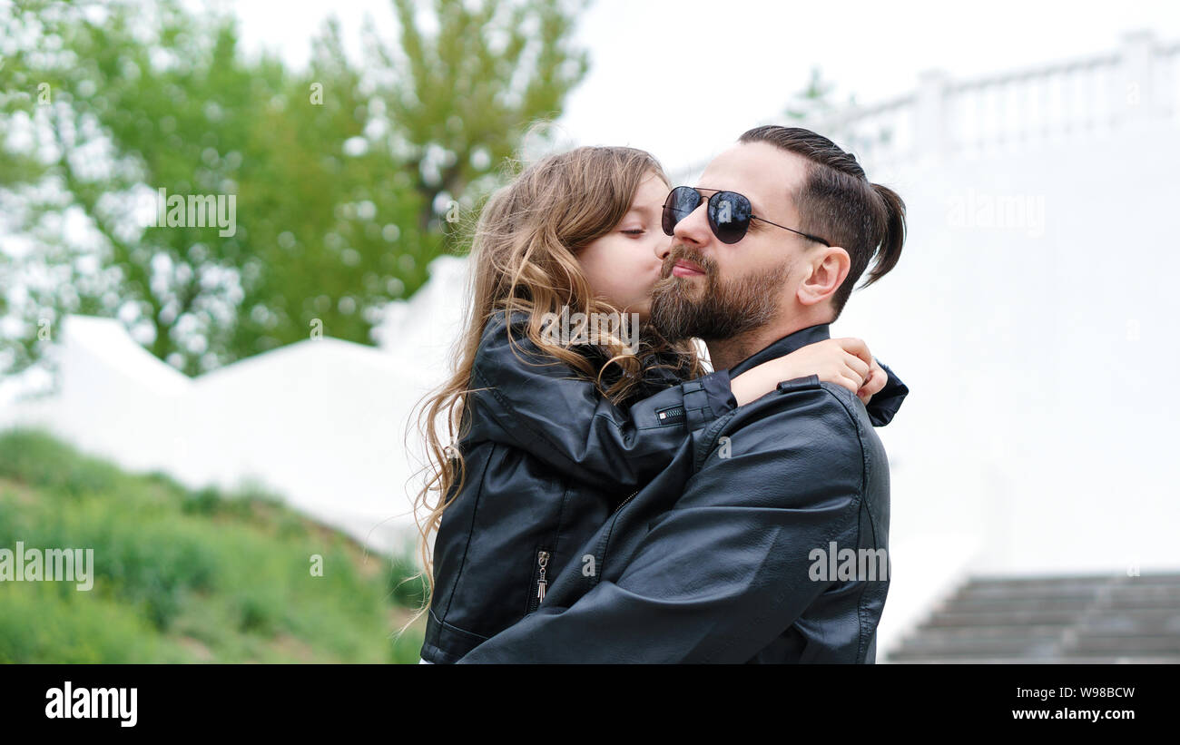Fashionable stylish family for a walk. Daughter in the hands of dad. Happy childhood. Man's early experience. Time together. Family look. Urban casual Stock Photo