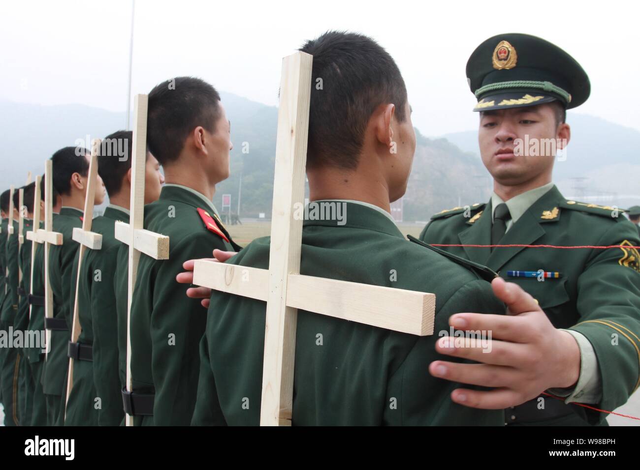 An officer of Armed Police straightens other officers with crosses tied to their backs during a military training in Hangzhou, east Chinas Zhejiang pr Stock Photo
