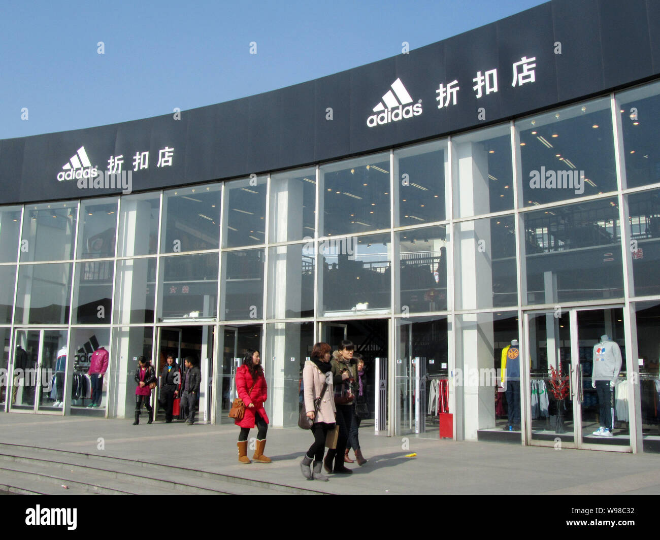 Shoppers walk past an Adidas discount store in Shanghai, China, 25 January  2011. Adidas said soaring demand from the United States, China and Russia  Stock Photo - Alamy