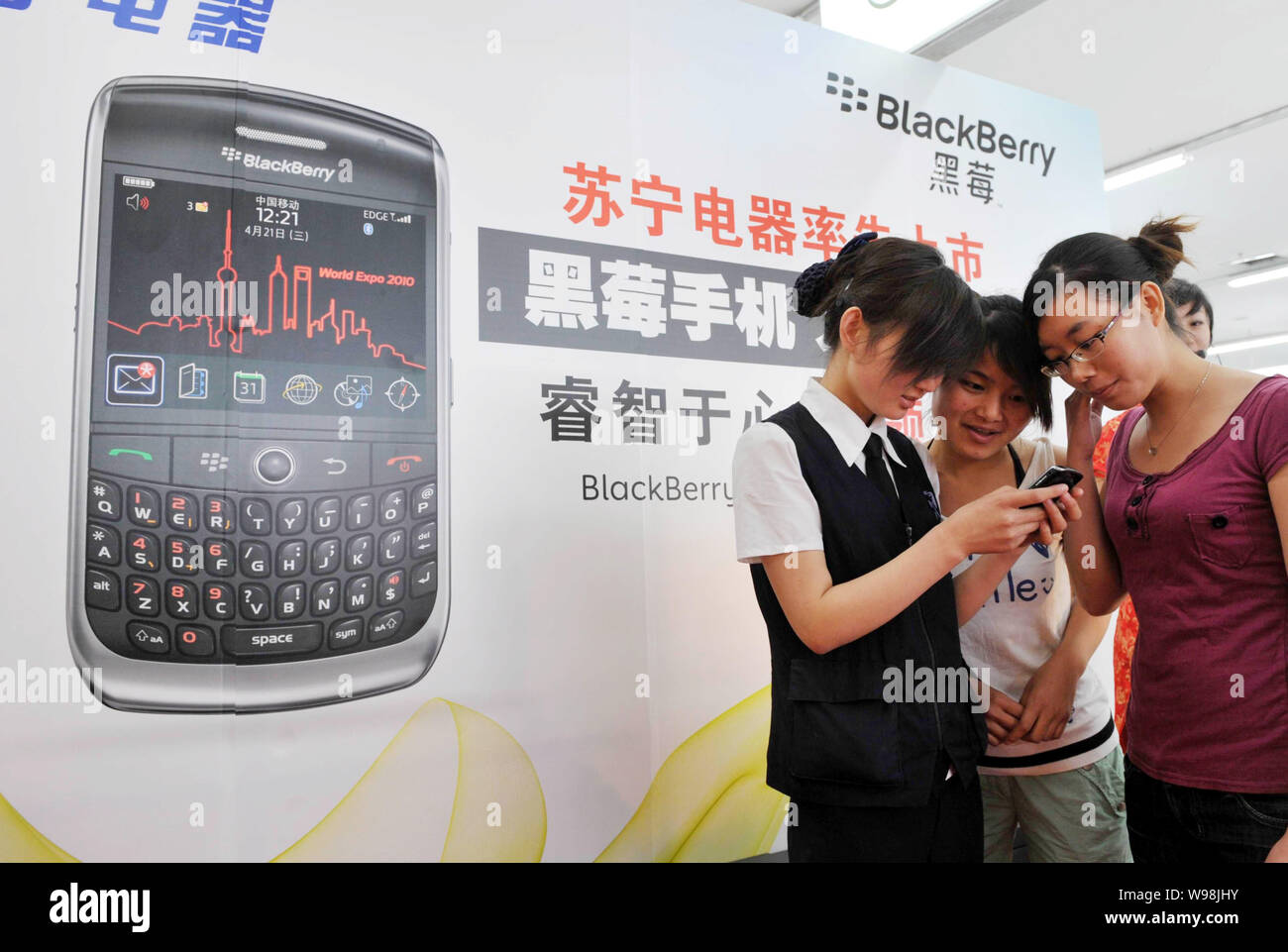 --FILE--A saleswoman introduces the BlackBerry 8910 Curve smartphone to customers at a Suning home appliance chain store in Beijing, China, 19 June 20 Stock Photo