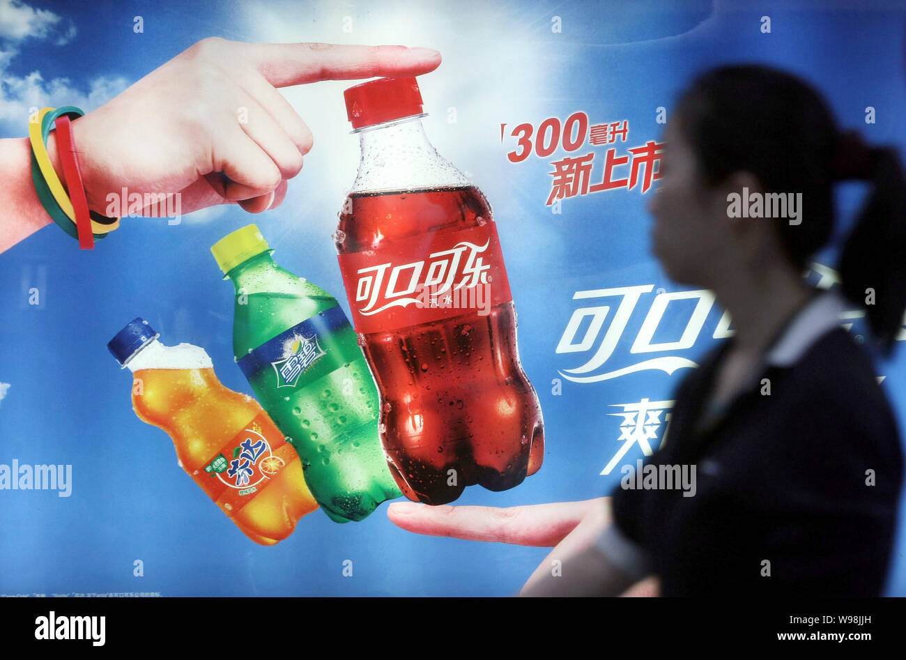 FILE--A young woman walks past an advertisement for Coca-Cola soft drinks  in Shanghai, China, 11 May 2011. Coca-Cola , the worlds largest soft dri  Stock Photo - Alamy