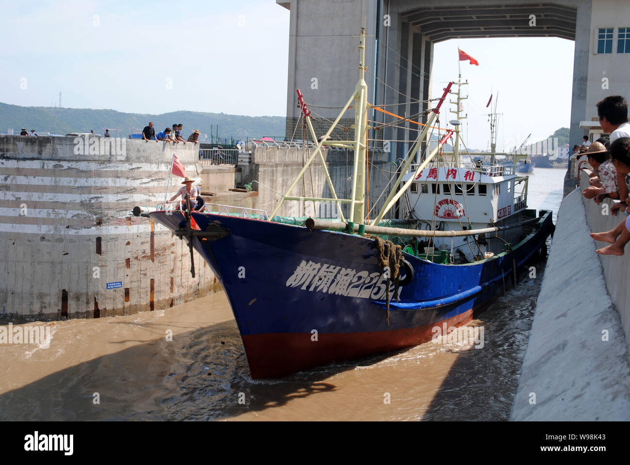 People watch a trawler driving into a safe harbor in Wenling, east Chinas Zhejiang province, China, 4 August 2011.   China has issued an orange alert Stock Photo