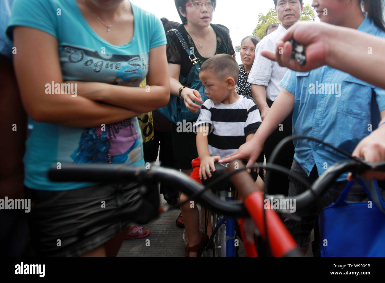A kid who witnessed a staff injuring eight children at a daycare center is picked up by his parent at the center in Shanghai, China, 29 August 2011. Stock Photo