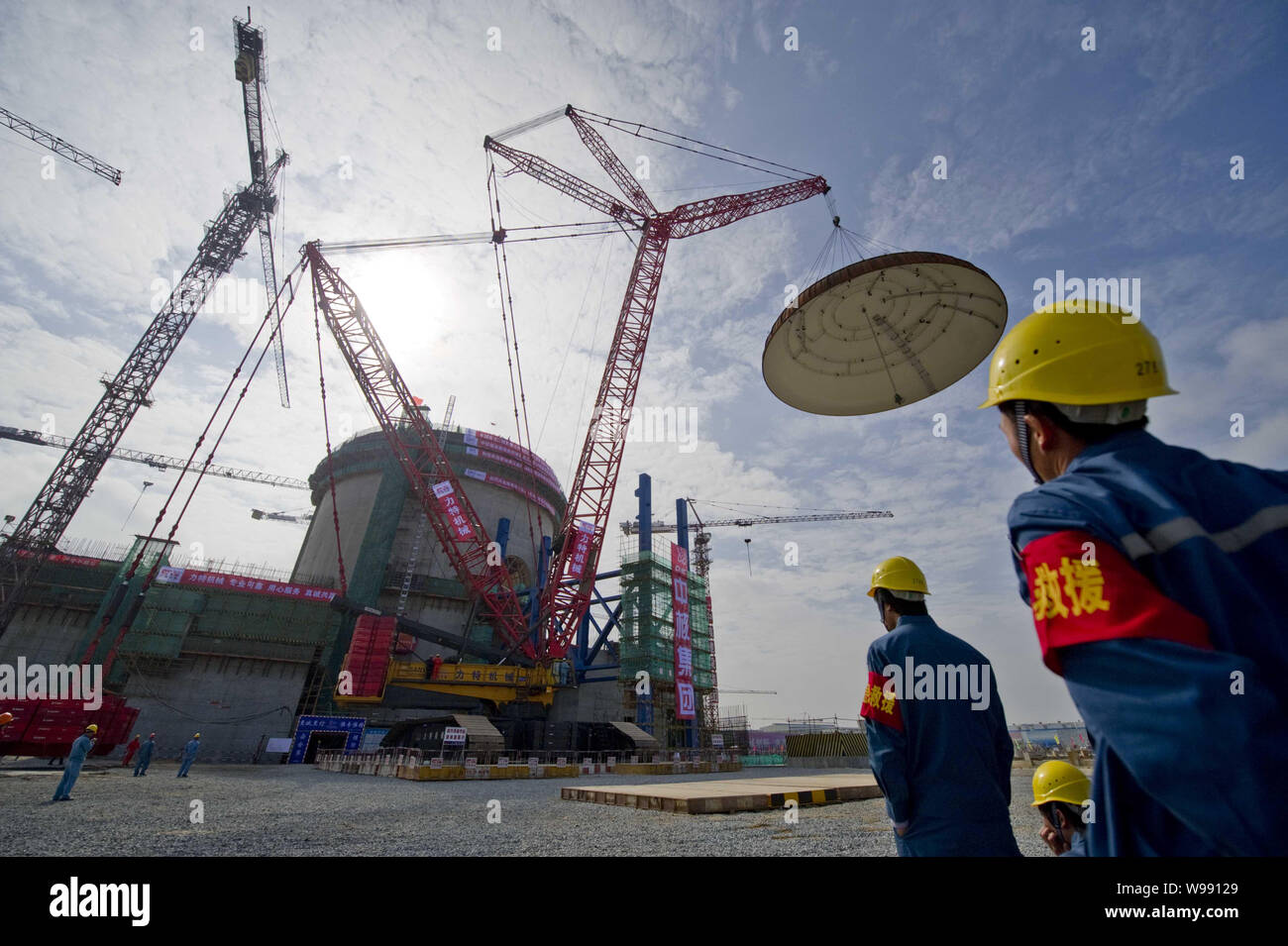 Workers watch the dome of the containment structure for the No.1 ...