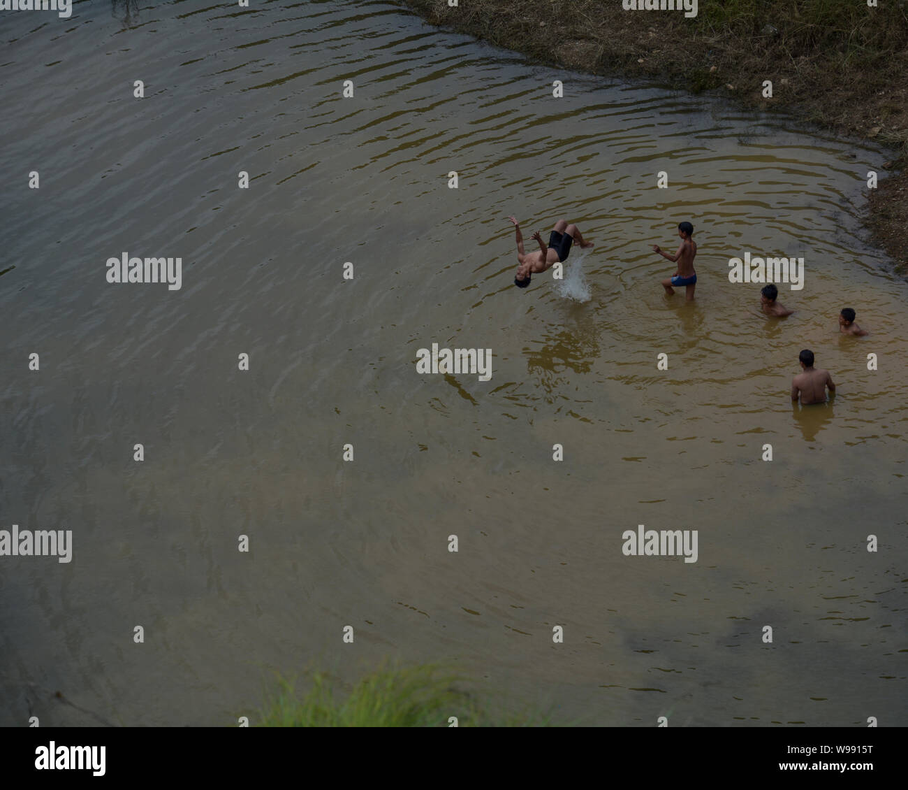 Boys at Chovar, Nepal enjoy swimming on water collected on the bottom of two hills to beat the heat. Stock Photo