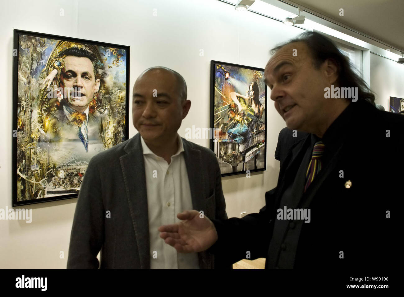 German-born artist Werner Hornung (R) shows visitors art works at an art exhibition featuring the works of him and Pal Sarkozy, father of French Presi Stock Photo