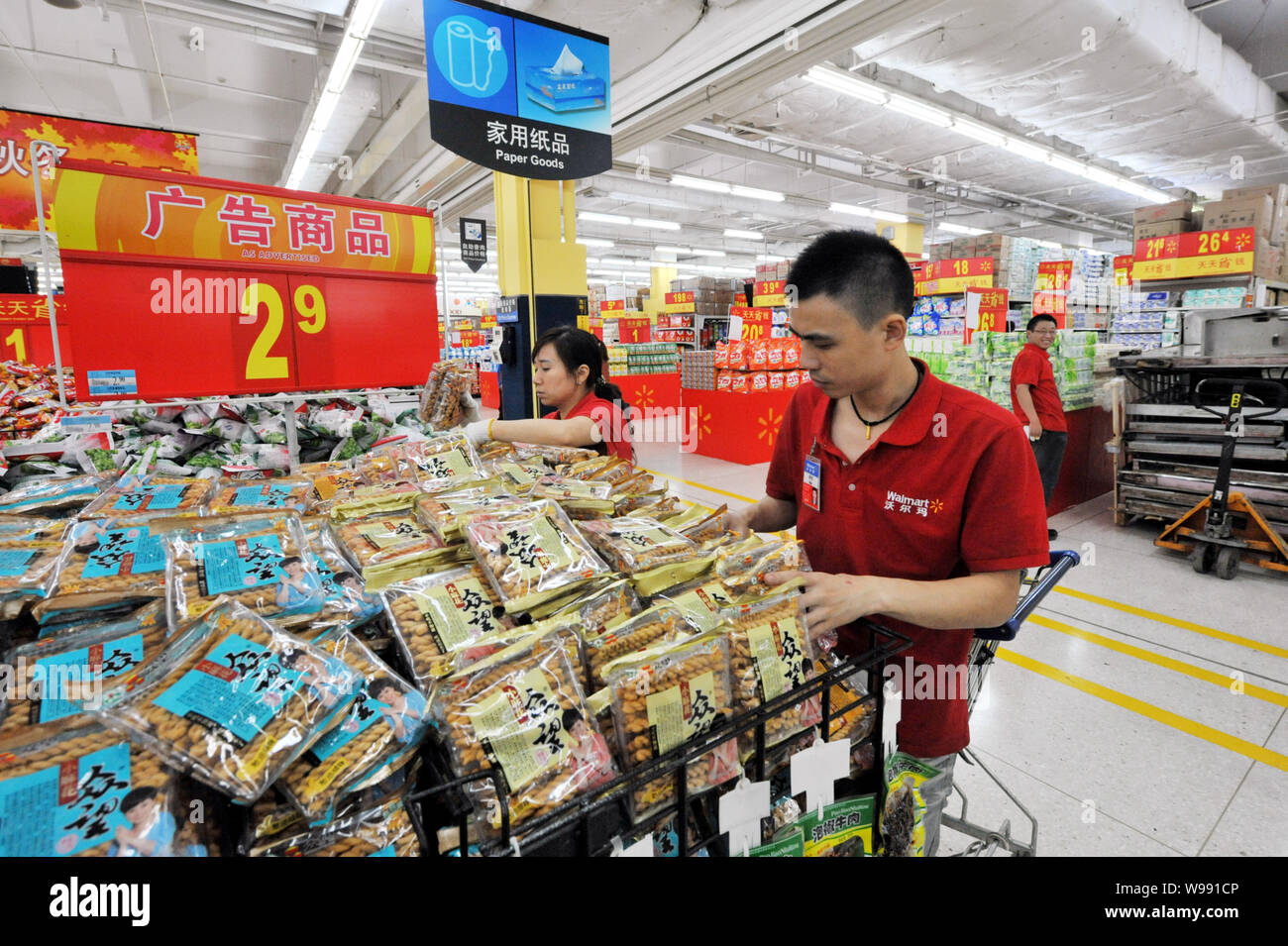 Chinese employees put bags of snack on the shelf in preparation for the reopening of a WalMart