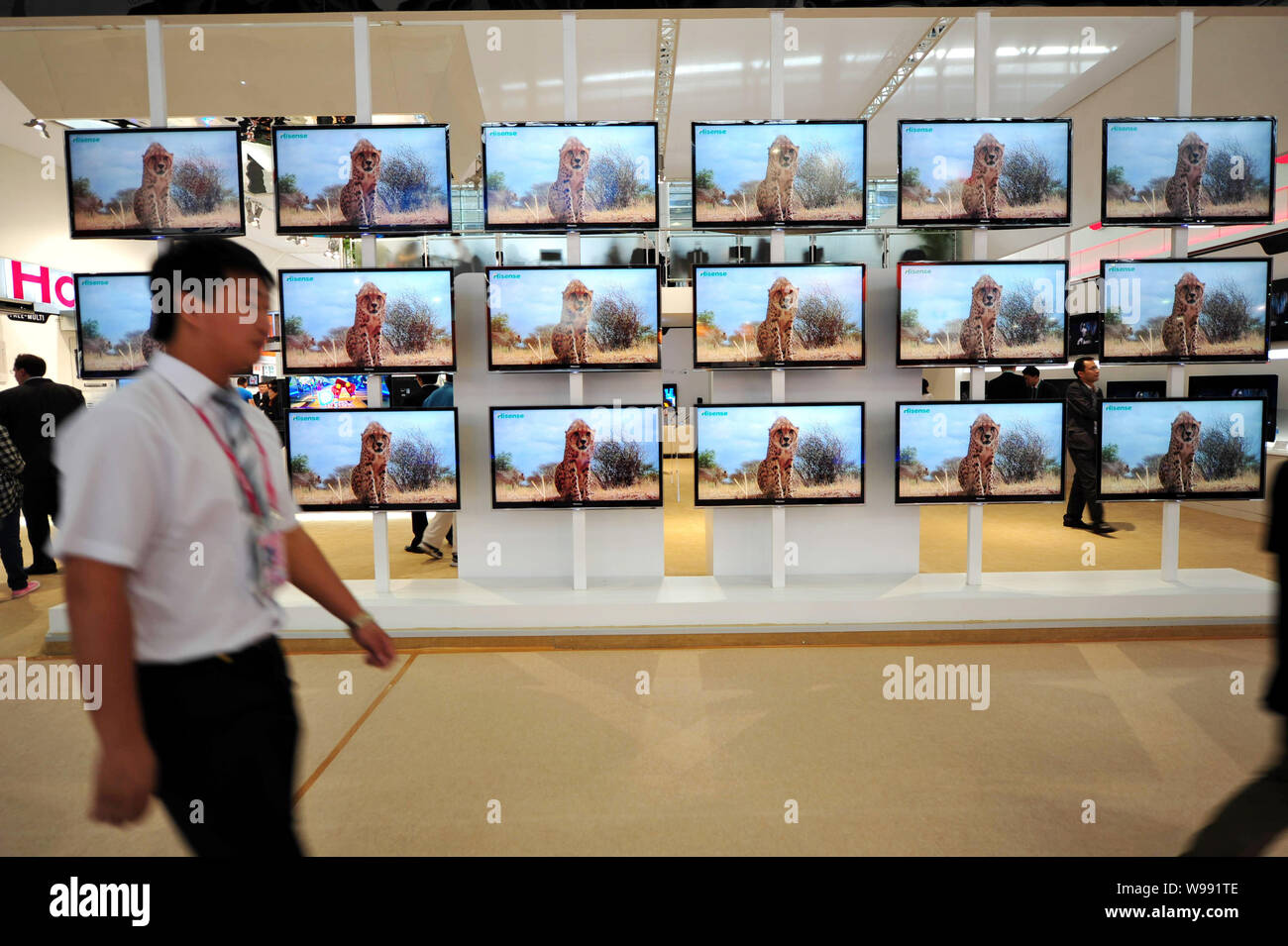 A visitor walks past a wall of Hisense flat-panel televisions during the 110th China Import and Export Fair, known as the Canton Fair, at the China Im Stock Photo