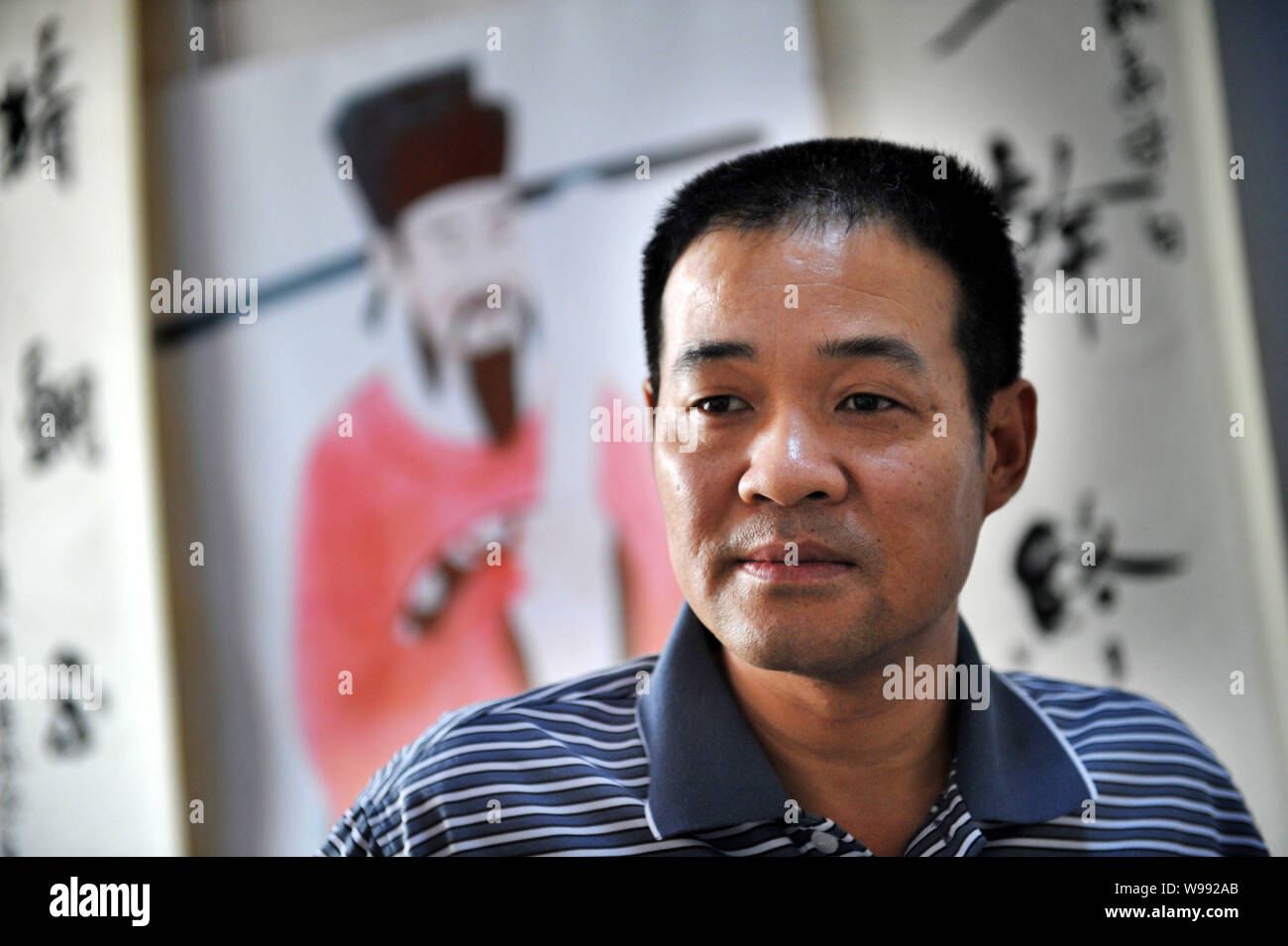 Bao XunAn, a descendant of ancient Chinese judge Bao Zheng, stands in front of a painting of Bao