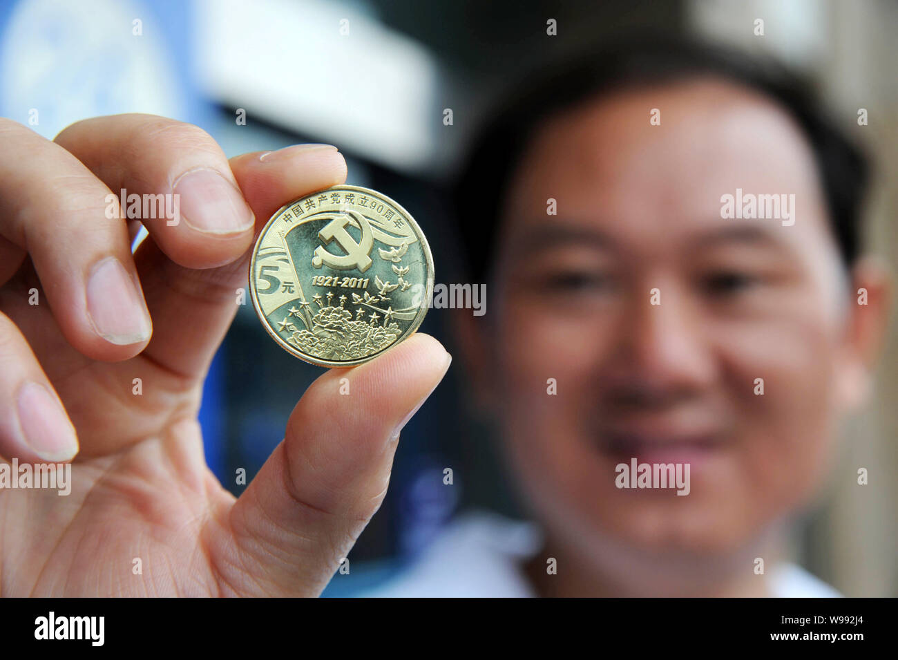 A man shows a commemorative coin marking the 90th anniversary of the ...