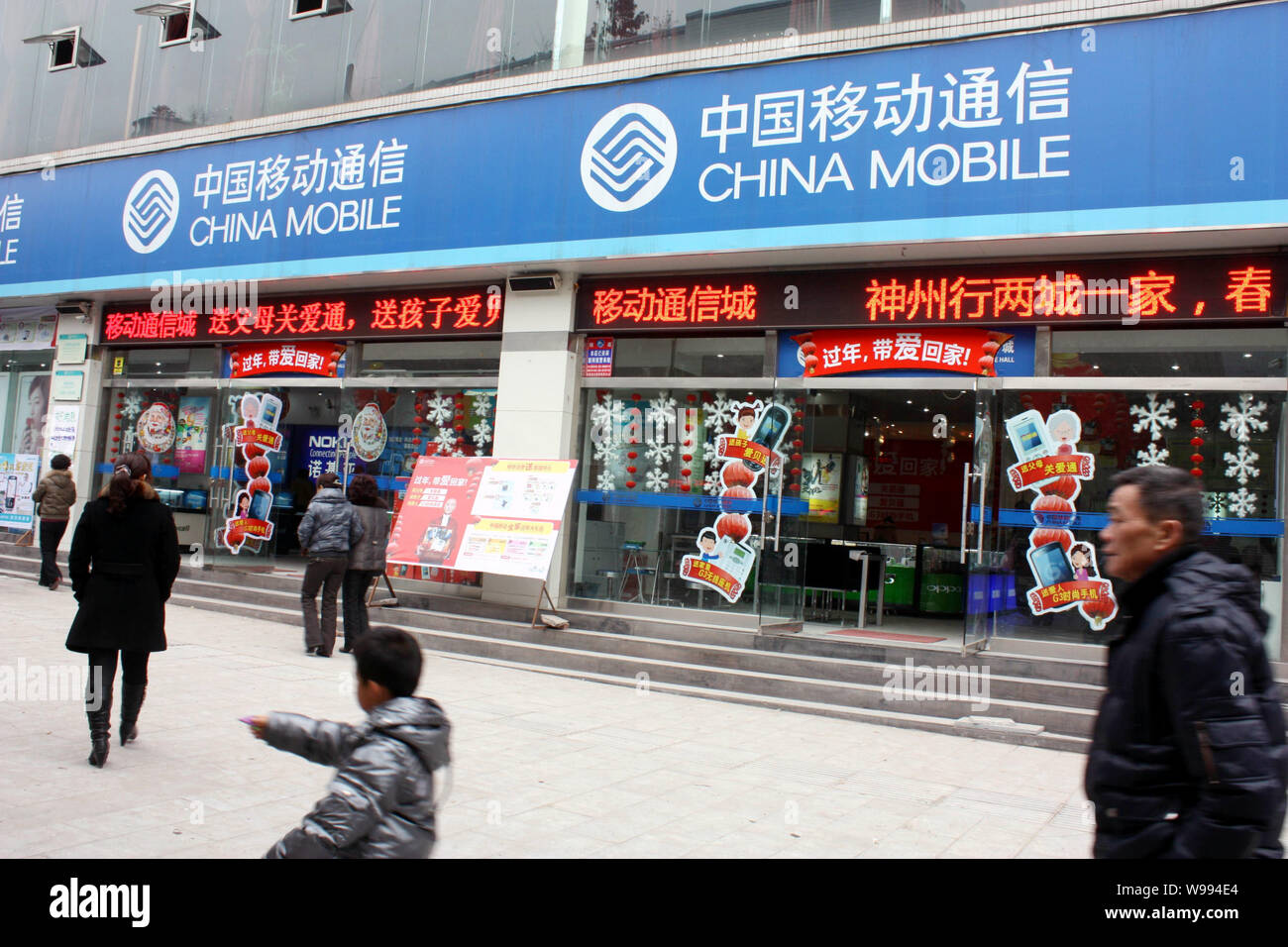 Local residents walk past a branch of China Mobile in Chongqing, China,  January 10, 2011. China Mobile Ltd, the worlds biggest phone carrier by  mark Stock Photo - Alamy