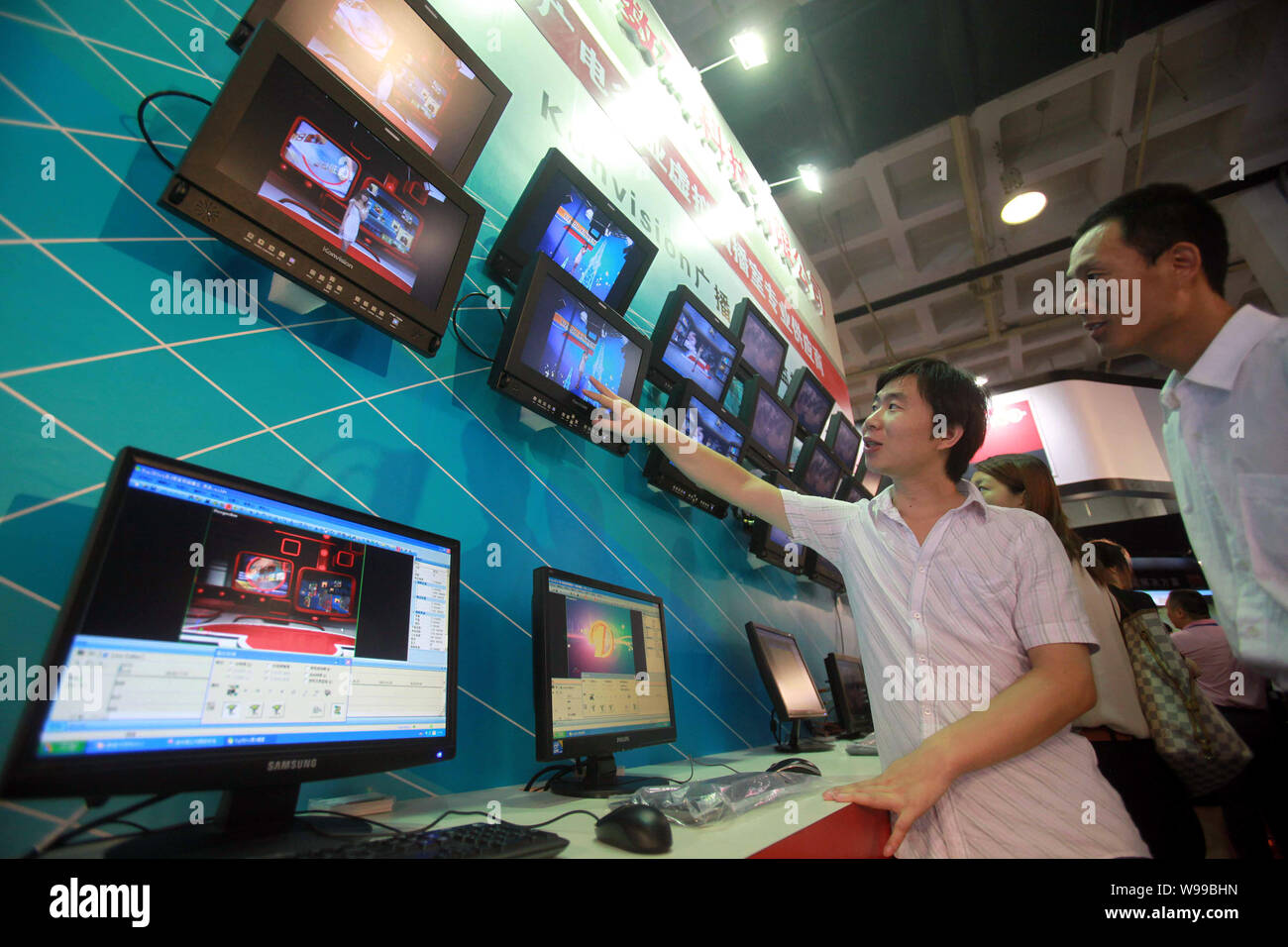 A Chinese worker introduces high definition monitors to visitors during
