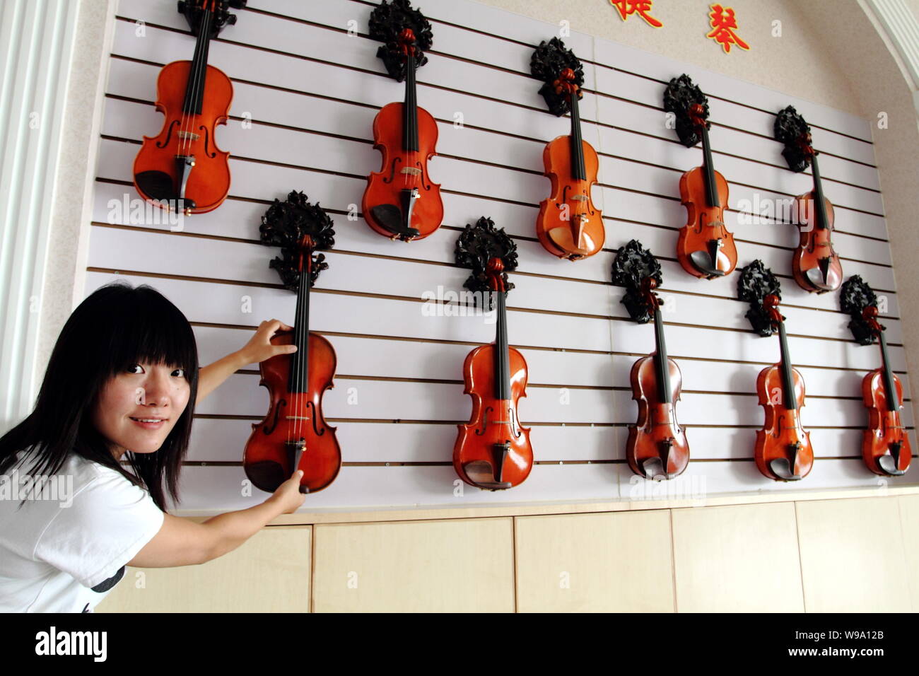 Perca pierna Camión golpeado A Chinese worker hangs up newly-made violins in the showroom at the factory  of Beijing Huadong Musical Instrument Corp. Ltd. in Donggaocun town, Pingg  Stock Photo - Alamy