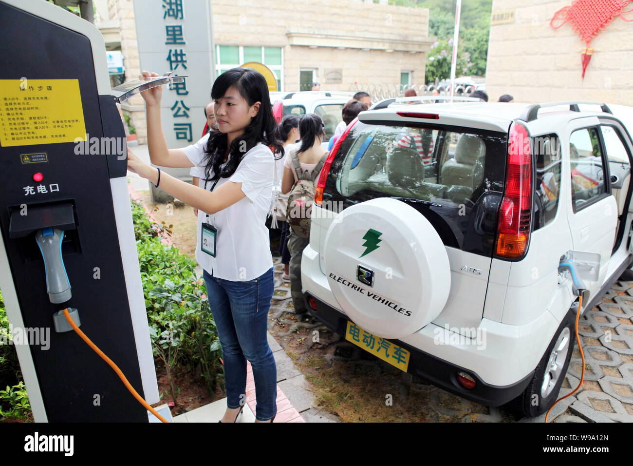A Chinese worker recharges an electric car during the launch ceremony of a charging station of State Grid Corporation of China in Xiamen city, southea Stock Photo