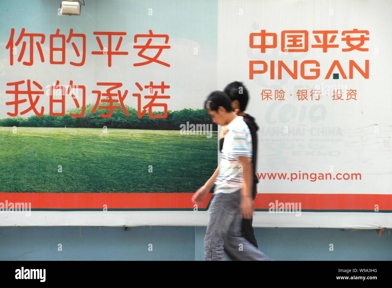--FILE--Local Chinese citizens walk past an advertisement for Ping An of China in Shanghai, China, 5 October 2009.   Ping An Insurance (Group) Co., Ch Stock Photo