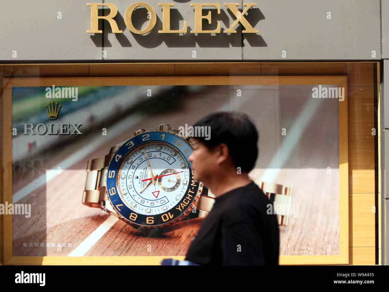FILE--A Chinese man walks past an advertisement for Rolex watches in  Shanghai, China, 23 October 2009. Household income in China surged in the  las Stock Photo - Alamy