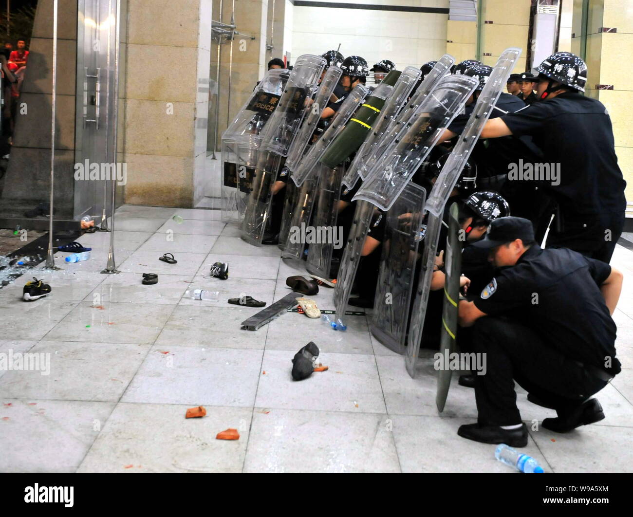 Chinese riot policemen stand behind their shields in front of local ...
