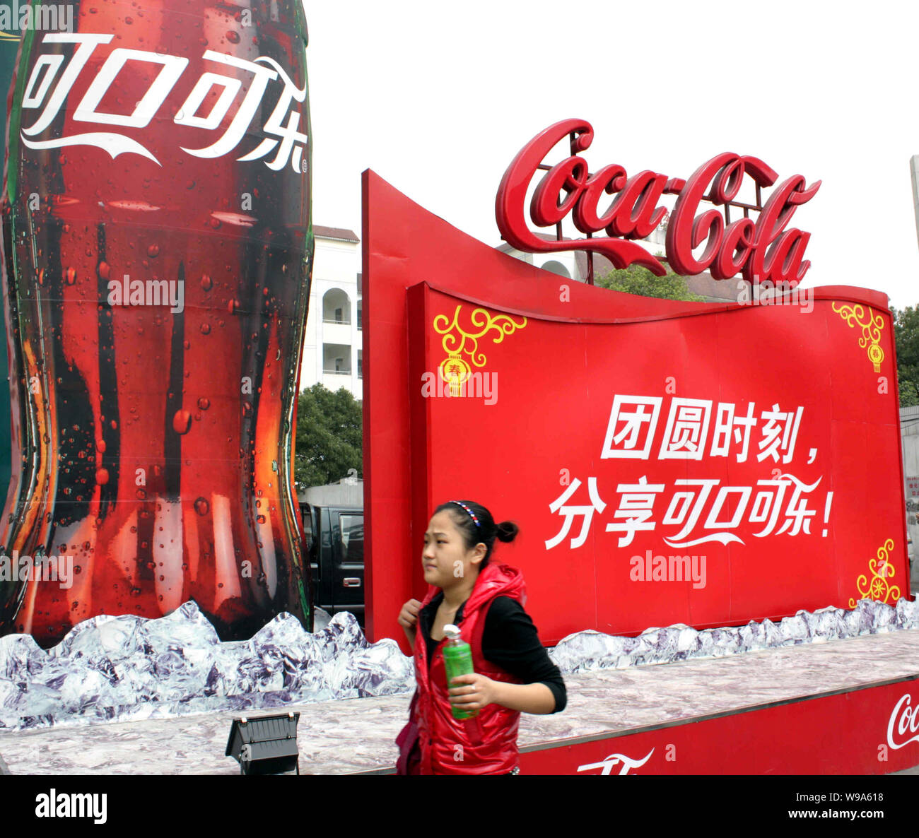 A Chinese woman walks past an advertisement of Coca Cola in Yichang ...