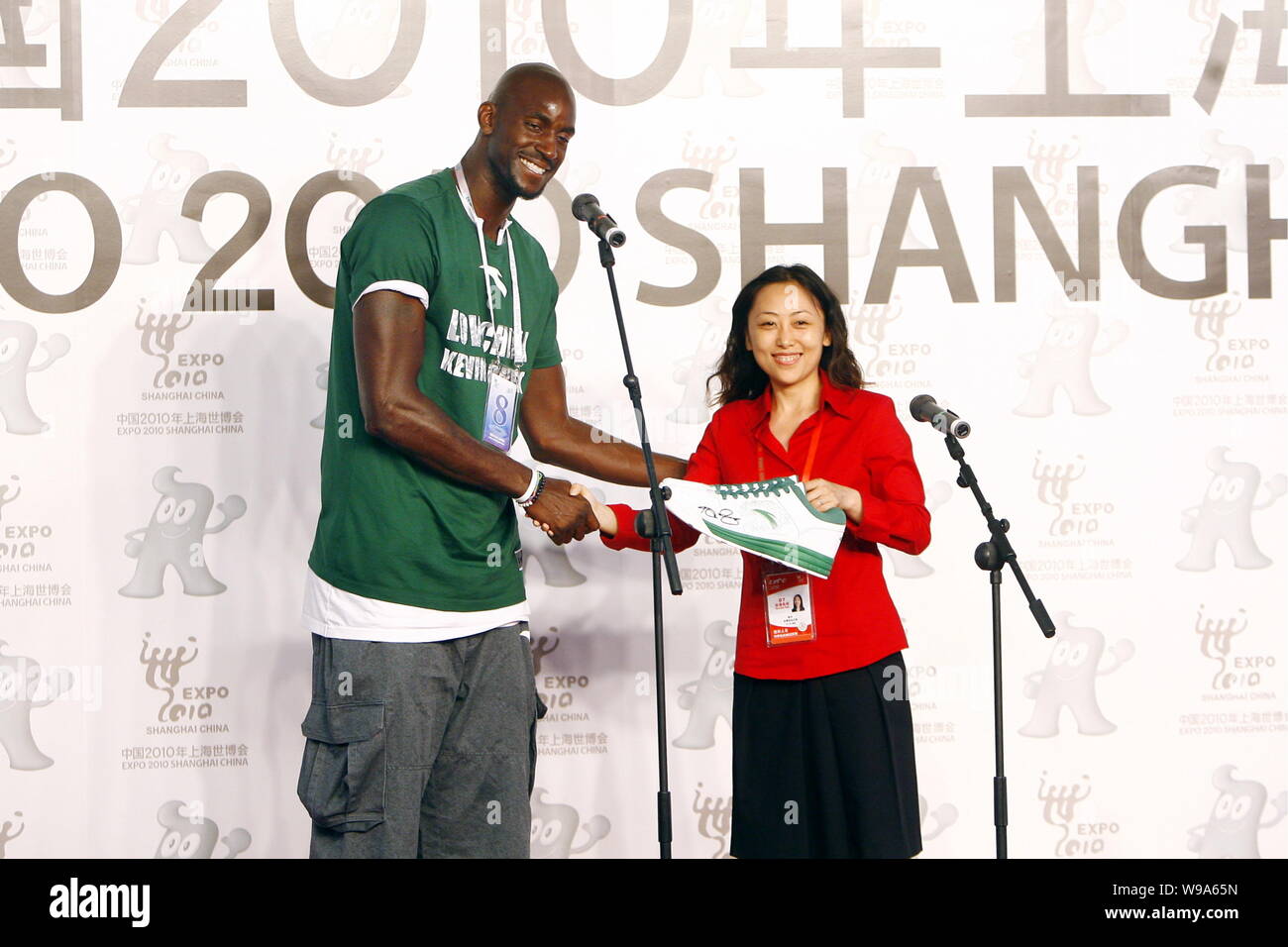 NBA basketball player Kevin Garnett of the Boston Celtics shakes hands with a Chinese foundation representative after presenting her a pair of sneaker Stock Photo